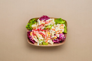 Vegetable salad in the paper food container on beige background with copy space