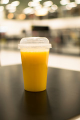 Orange juice isolated, plastic cup of fruit juice on white background