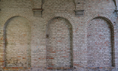 Background of a historic brick wall with several arches and recesses in the wall