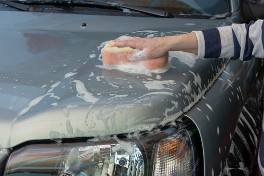 Mano con esponja lavando el coche