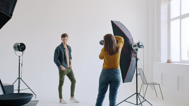 Slow motion of handsome guy modelling in studio working with professional photographer advertising for fashion magazine wearing stylish clothing. People and photography concept.
