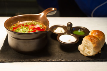 Ukrainian borsch with donuts, onion and garlic on a black dish