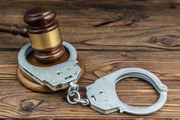 Gavel judge and handcuffs on a wooden table. The concept of crime and punishment, court, law....
