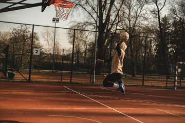 Street basketball player having training outdoor. He is making a good action. Basketball slam dunk.
