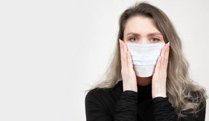 Woman in a medical mask. A young girl is afraid to get infected. Fever panic. Panic among the population during the epidemic. Place for an inscription on a light background. Fear. Disease