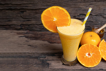 Orange juice fruit smoothies yogurt drink yellow healthy delicious taste in a glass slush for weight loss on wooden background.