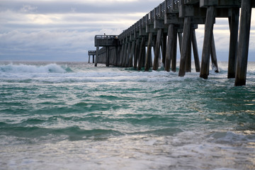 Scenic View of Pier at Panama City Beach FL with green Crashing Waves and Blue Clouds 