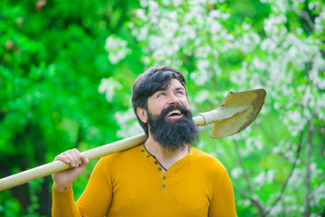 Gardening. Bearded man with shovel in garden. Garden tools. Gardener work. Farm. Work in garden. Spring. Backyard. Garden. Yard. Croft. Herbary. © Svitlana