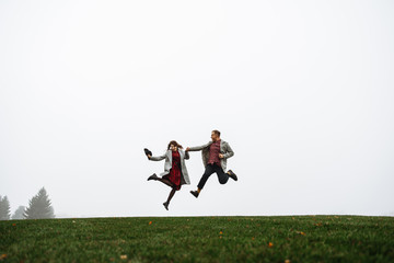 Loving couple have fun together, they jumping on the grass