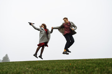Fototapeta na wymiar Loving couple have fun together, they jumping on the grass