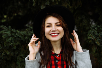 Close up portrait of a beautiful smiling girl in a hat and with red lipstick, outdoors