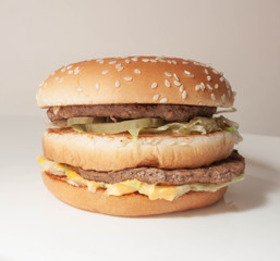 Burger with two cutlets on a white plate and a light background