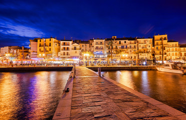 View from the waterfront of Calvi on the old town with historic buildings at night. Bay with yachts...