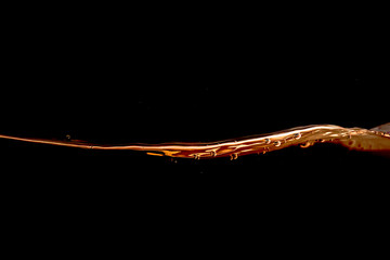 big wave of oil  splash and air bubbles isolated  with  black background . Yellow Gold water wave abstract background isolated