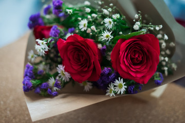 bouquet of roses arrangements of flowers in a paper wrapper on wooden background