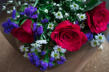 bouquet of roses arrangements of flowers in a paper wrapper on wooden background