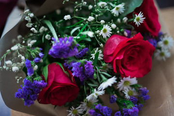 bouquet of roses arrangements of flowers in a paper wrapper on wooden background