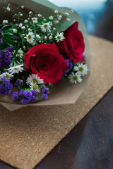 bouquet of roses arrangements of flowers in a paper wrapper on wooden background