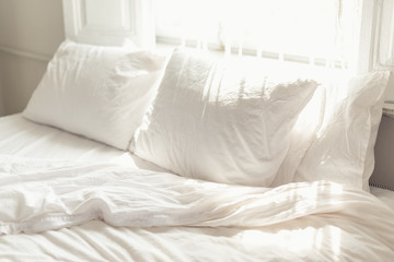 Fototapeta na wymiar White pillow and bedclothes in bright bedroom