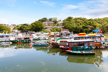 Fototapeta na wymiar Fishing and tour boats dock at the busy harbor in Sai Kung, Hong Kong, a town famous for its quaint fishing villages and the floating seafood market