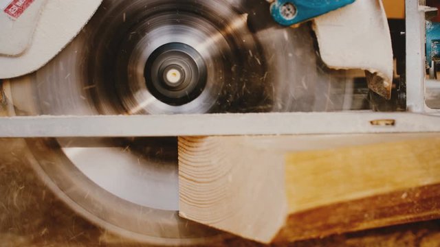 Beautiful close-up background of circular buzz saw cutting a piece of wood, carpenter at manufacturing work slow motion.