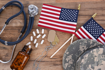 Military and Veterans Health Care Concept. Camo hat, dog tags, stethoscope, pills, and American...