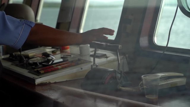 Close up shot of an Indonesian captain's hand adjusting the speed levers of his ship, Slow Motion through window view