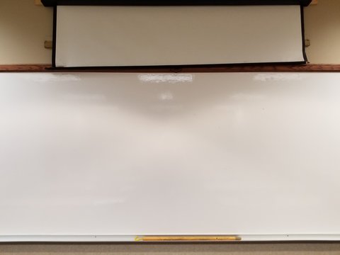 Blank glossy white board at front of classroom