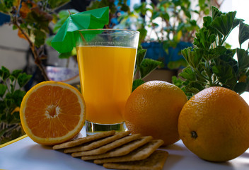 jugo de naranja en vaso de vidrio con sombrilla pequeña color verde, con media naranja en el lado...