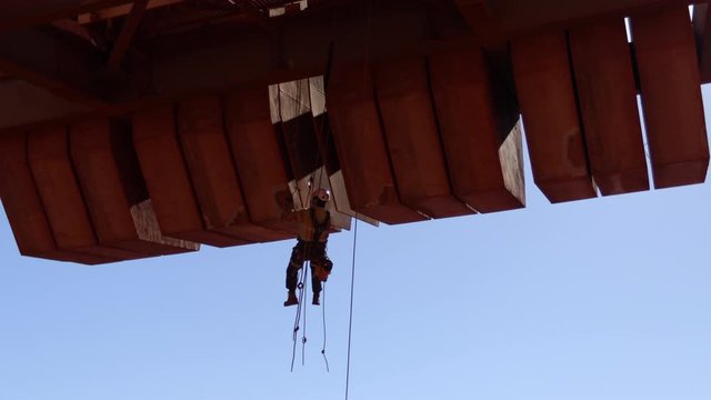 4K footage of industry rope access technician inspector abseiling with 2 safety rope hanging working at height  inspecting concrete spalling on counterweight construction site Sydney, Australia