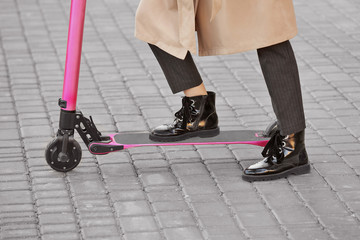 Young woman with kick scooter on city street