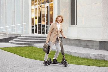Young businessman with kick scooter outdoors