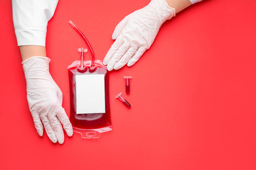 Hands of doctor with blood pack for transfusion and test tubes on color background