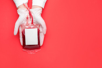 Hands of doctor with blood pack for transfusion on color background