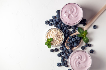 two fresh blueberry yogurt with blueberries and cereals on a white texture table, ingredients for cooking