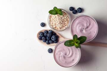 two fresh blueberry yogurt with blueberries on a white texture table, top view