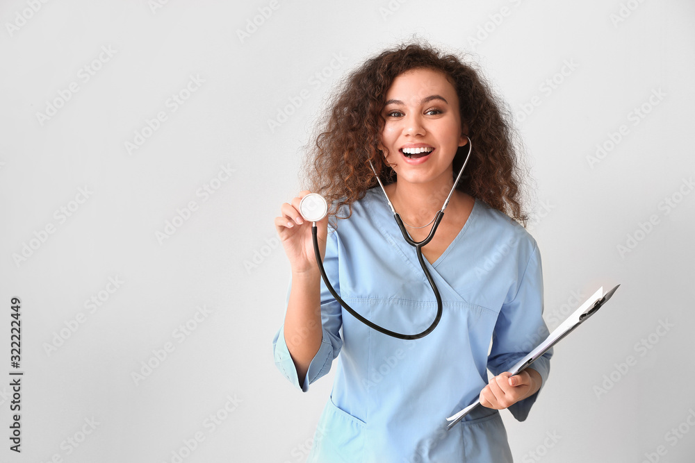 Sticker young african-american nurse with stethoscope on light background