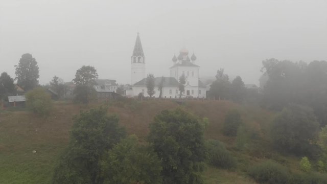 Aerial. Flight over the Orthodox church In the morning fog. Bank of the Volga River. Russia. Kineshma.