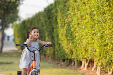 Fototapeta na wymiar Cute Little Girl Riding Her Orange Bike in the Park 