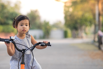 Cute Little Girl Riding Her Orange Bike in the Park 