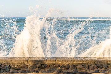 Obraz premium Close up of a stone wall where waves are crashing over, at the ocean, at Waikiki Beach in Honolulu, Hawaii.