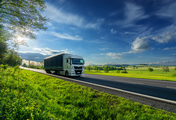 White truck driving on the asphalt road in a spring rural landscape