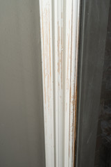 Trim moulding around a door frame is scratched and reveals bare wood underneath the paint