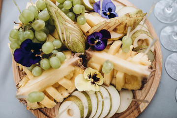 fruit slices of pineapple, pear and grape on a wooden board