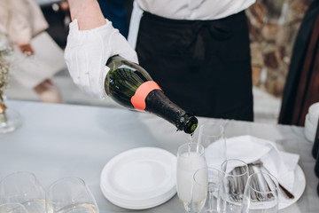 a waiter in white gloves pours champagne into a glass