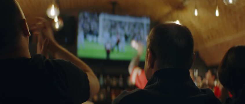 HANDHELD Model released, fans watching a game on a large TV in a sport pub. Shot on ARRI Alexa Mini with Atlas Orion 2x Anamorphic lens