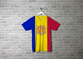 Andorra flag on shirt and hanging on the wall with brick pattern wallpaper.
