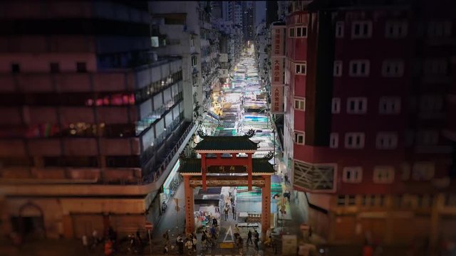 Temple Street market at night in Mongkok, Kowloon, Hong Kong, China. Locked wide shot. Tilt-shift effect