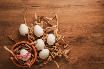 Easter, tied egg with red ribbon in wooden bowl and white eggs on brown paper on wooden table
