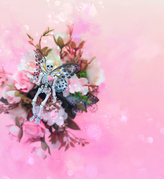 small skeleton with flowers on abstract pink background. surreal creative concept. artistic magic image.
